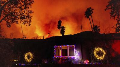 A helicopter drops water on the Palisades Fire in 1738154719995